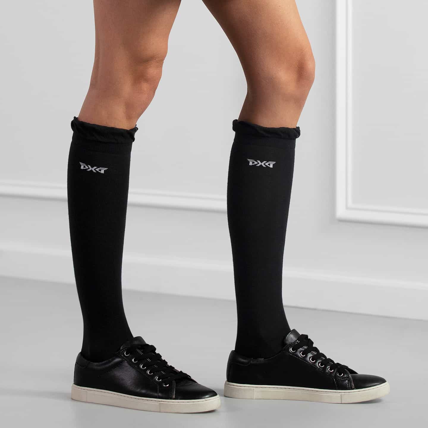 PXG women's black ruffle knee golf socks with ruffles at the top and a white PXG logo on a white background