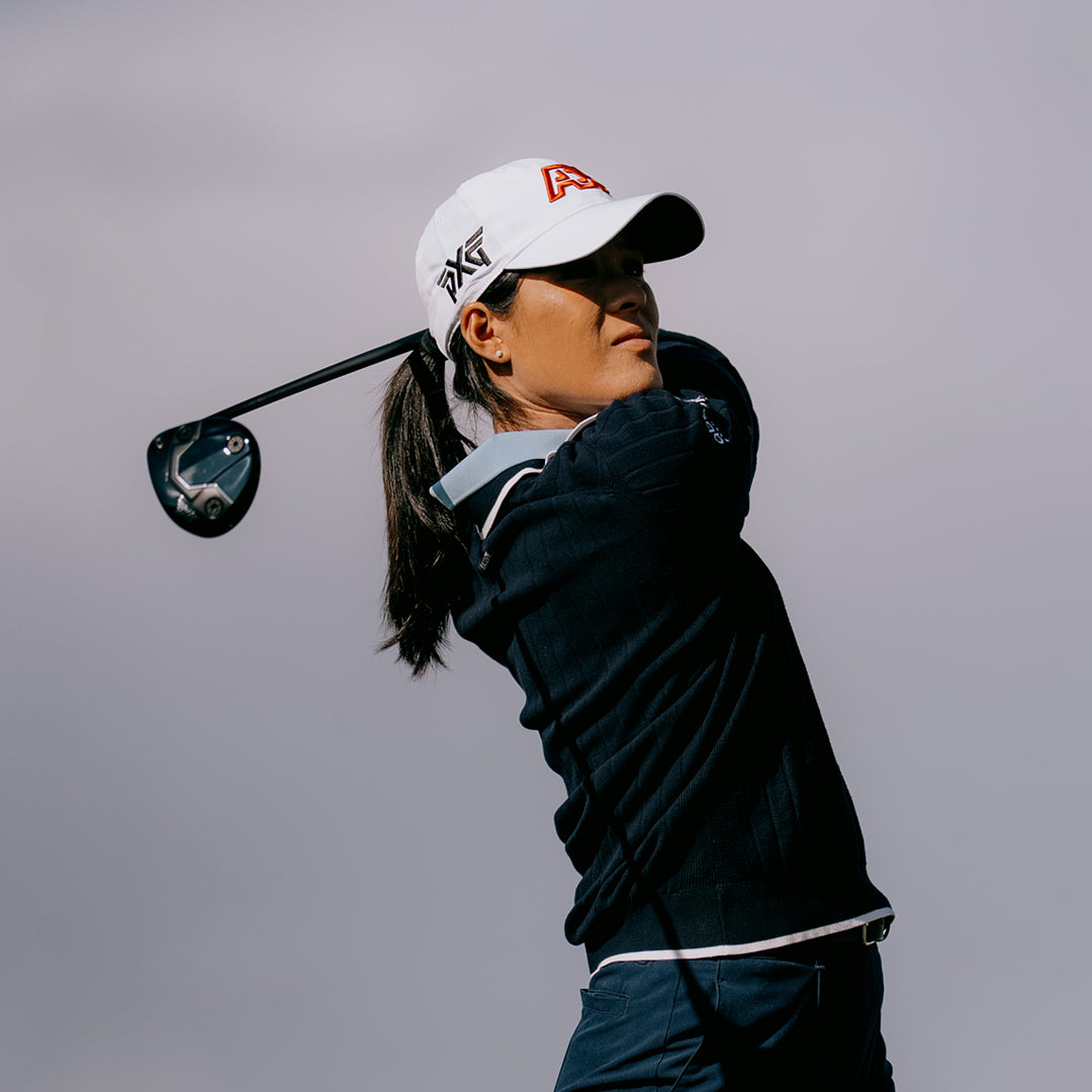 LPGA Tour Pro Celine Boutier wearing a PXG Golf Hat with a PXG Golf Club against a gray sky.