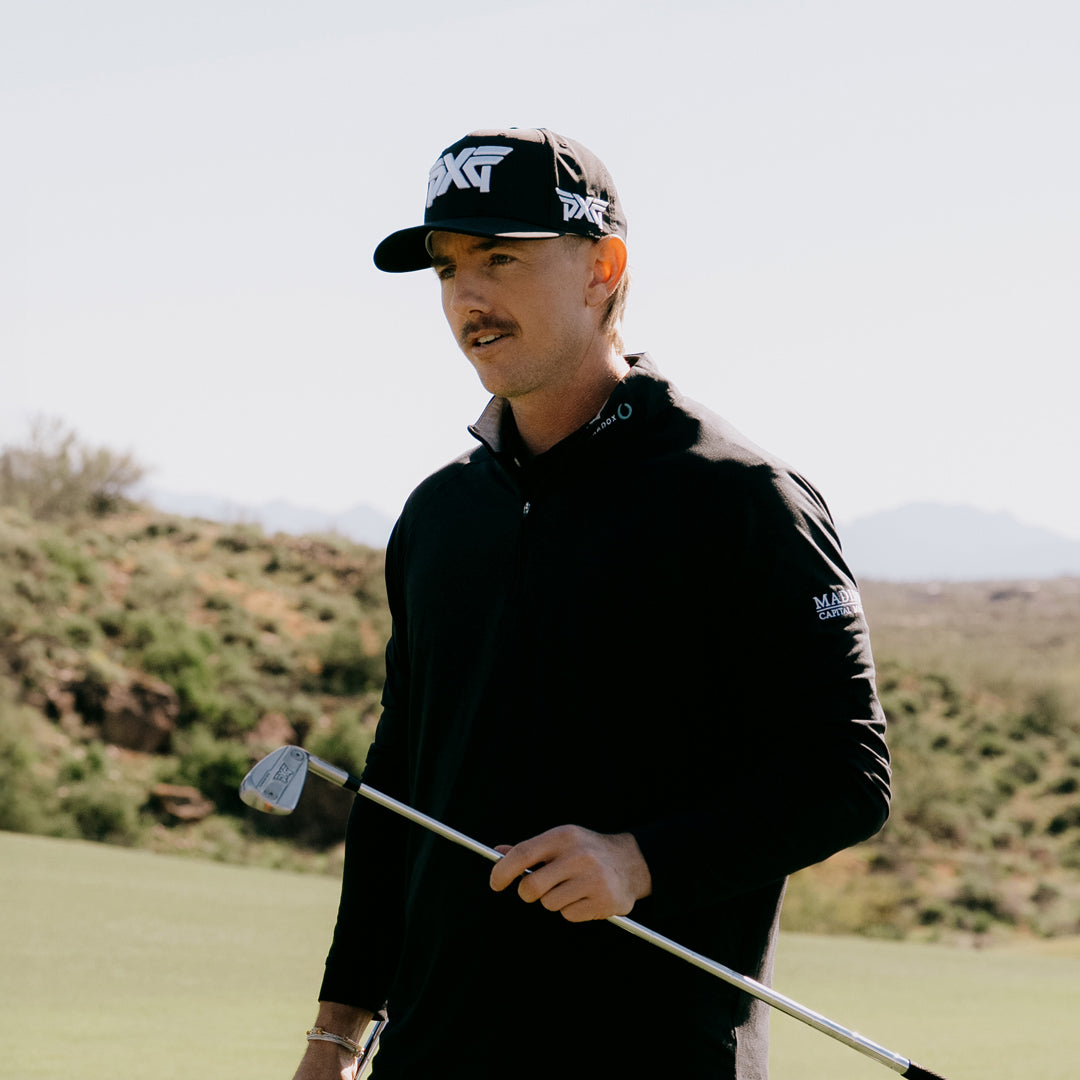 PGA Tour Pro Jake Knapp wearing a PXG Golf Hat on a golf course holding a PXG Golf Club.