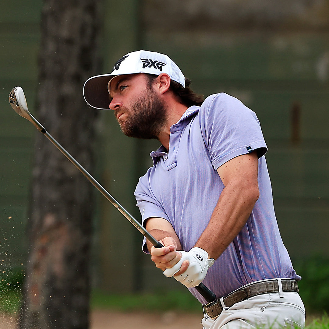 Pro Joey Garber wearing a PXG Hat and swinging a golf club on a golf course.