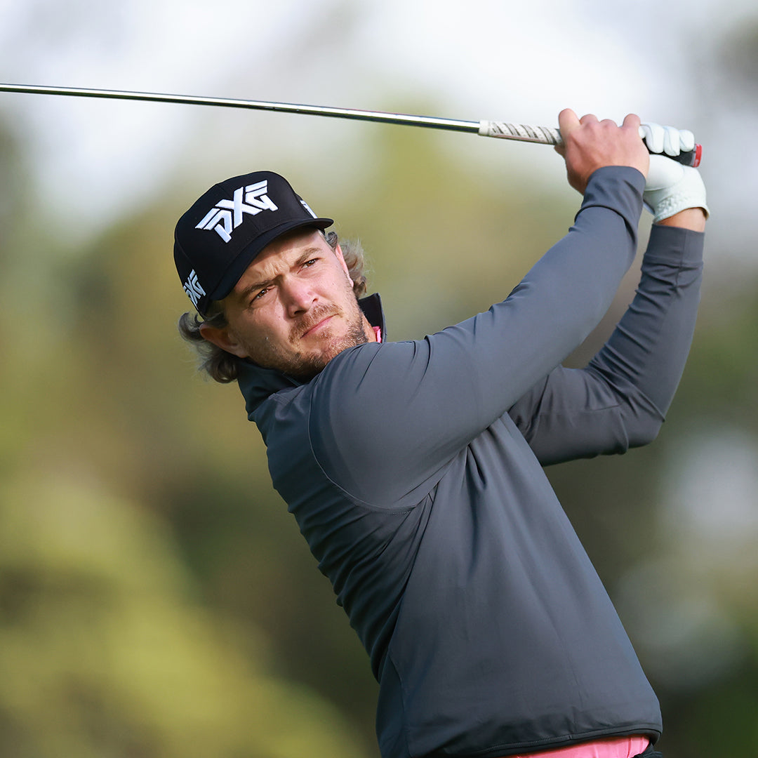 Pro Sebastian Cappelen wearing a PXG Hat and swinging a golf club on a golf course.